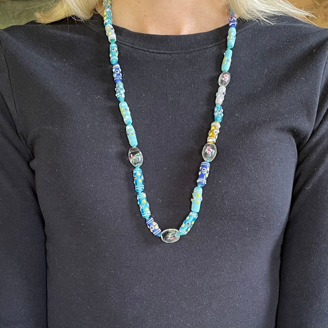Antique Venetian glass African trade bead necklace in turquoise and blue with eye beads, wedding cake beads and encased floral lampwork beads shown on model