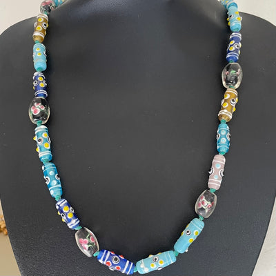 Antique Venetian glass African trade bead necklace in turquoise and blue with eye beads, wedding cake beads and encased floral lampwork beads shown on bust