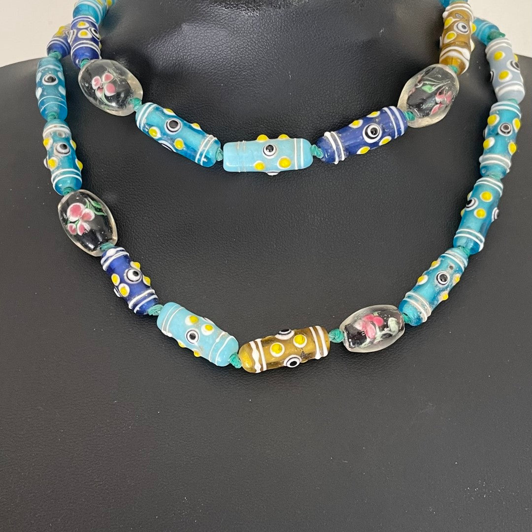 Antique Venetian glass African trade bead necklace in turquoise and blue with eye beads, wedding cake beads and encased floral lampwork beads shown doubled on bust
