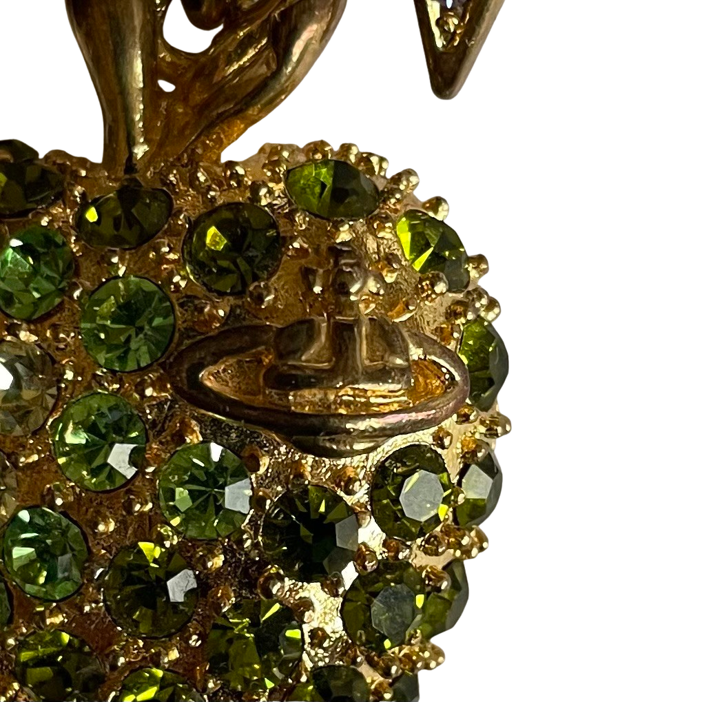 close up of orb on gold tone Vivienne Westwood vintage necklace with a colorful bow and green apple pendant on a white background