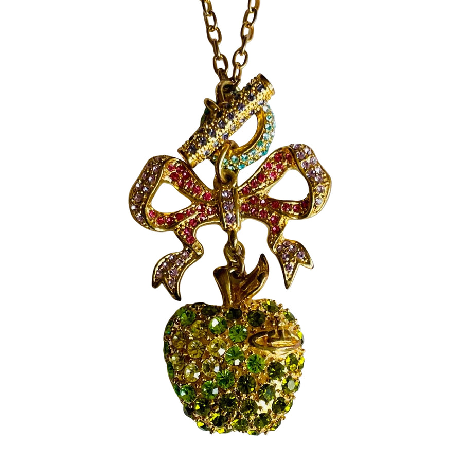 Gold tone Vivienne Westwood vintage necklace with a colorful bow and green apple pendant on a white background