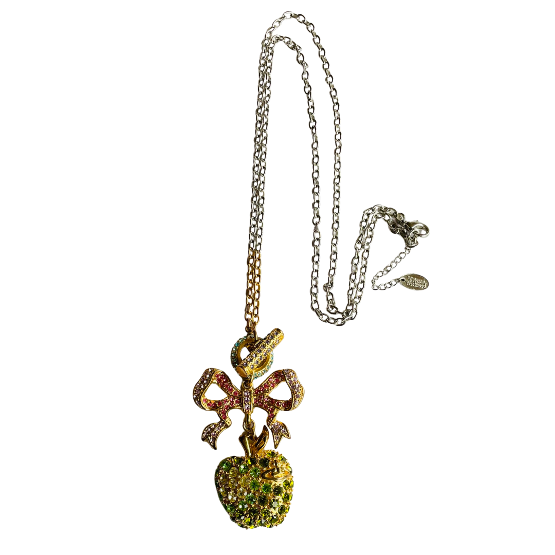 Gold tone Vivienne Westwood vintage necklace with a colorful bow and green apple pendant on a white background