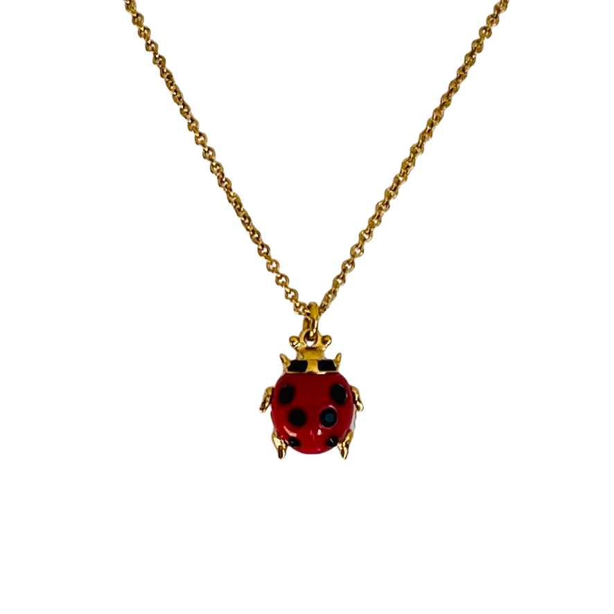 Close-up of a Vivienne Westwood Sylvana ladybird necklace in gold-tone, featuring a red enamel body with black crystals, dangling orb charm, and hallmark tag.