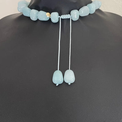 reverse of Lola Rose milky-aqua blue quartzite statement necklace with hand-knotted pillow nugget beads and a round yellow-gold-tone charm on an adjustable cord