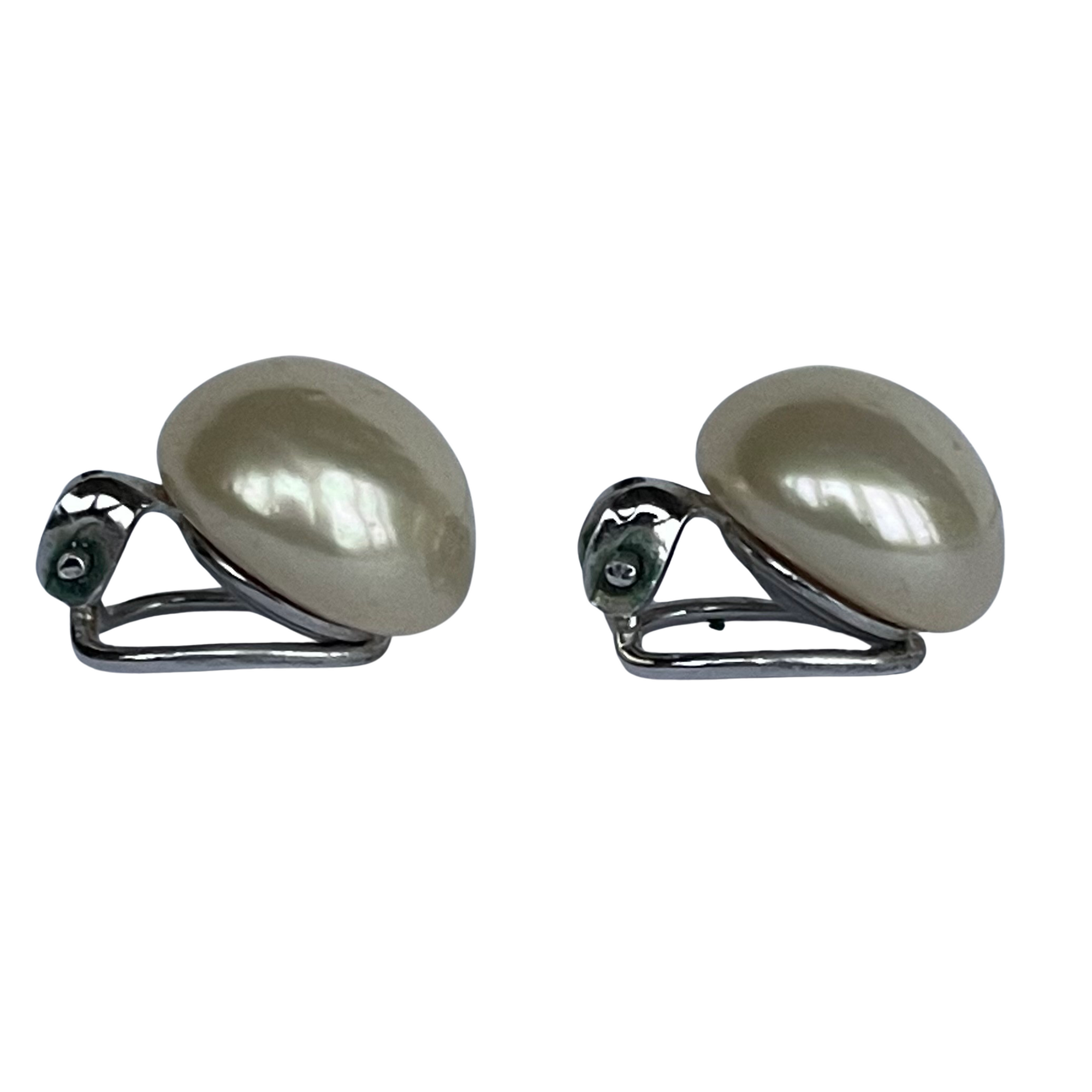 side view of Pair of vintage Christian Dior button pearl earrings on a white background