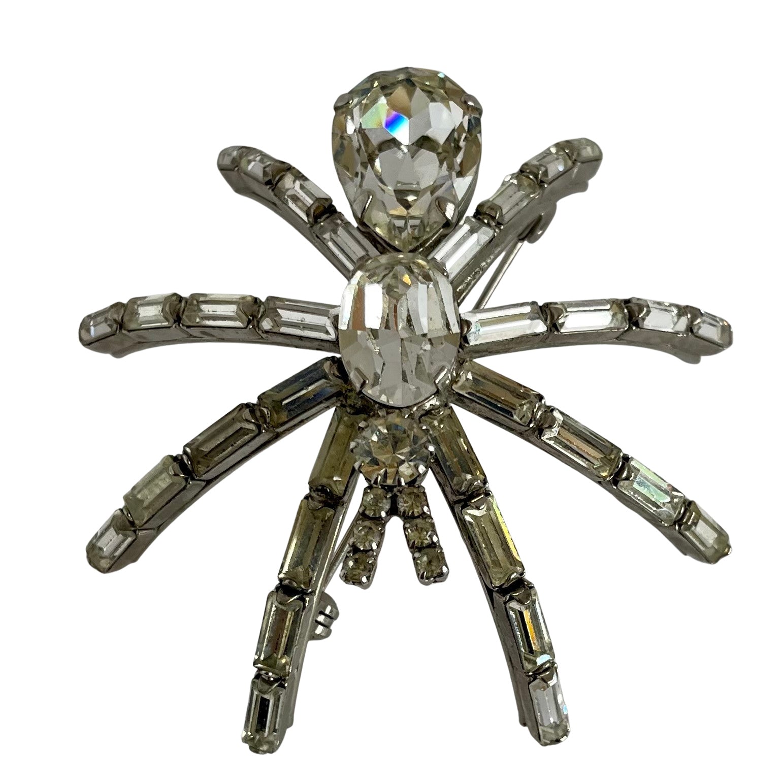 a very large 1980s Butler & Wilson spider brooch with clear faceted crystals on a silver-tone metal base, displayed  on a white background.