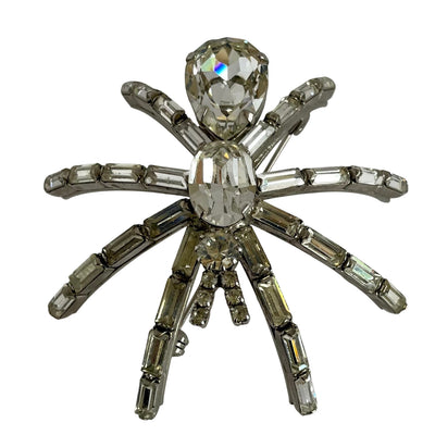a very large 1980s Butler & Wilson spider brooch with clear faceted crystals on a silver-tone metal base, displayed  on a white background.