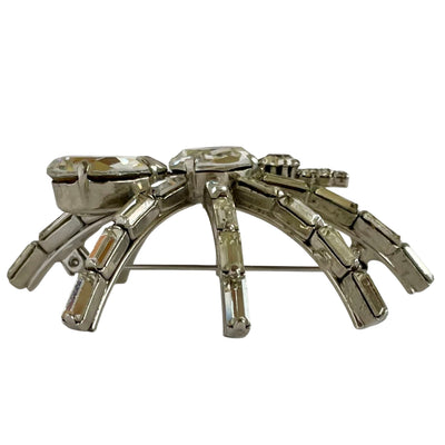 side view of a very large 1980s Butler & Wilson spider brooch with clear faceted crystals on a silver-tone metal base, displayed  on a white background.