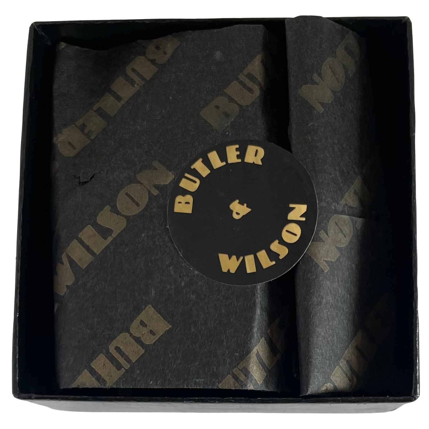 A black Butler & Wilson box complete with tissue from the 1980s on a white background. The box houses the early Butler & Wilson large spider brooch.