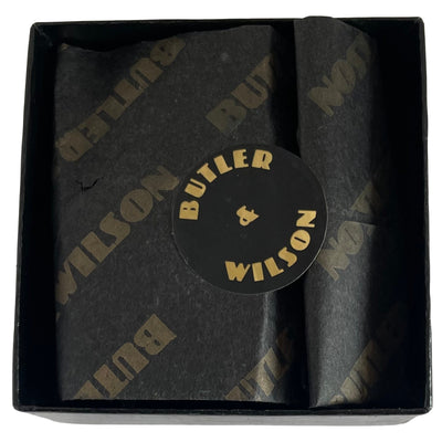 A black Butler & Wilson box complete with tissue from the 1980s on a white background. The box houses the early Butler & Wilson large spider brooch.