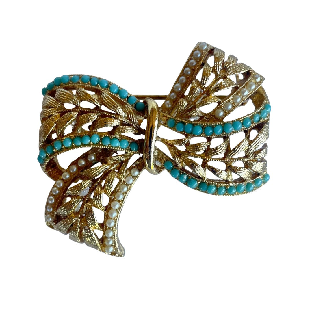 Vintage Sphinx A645 signed bow brooch in gold-tone textured metal with rows of turquoise beads and white faux pearls, showing a 3D ribbon effect.