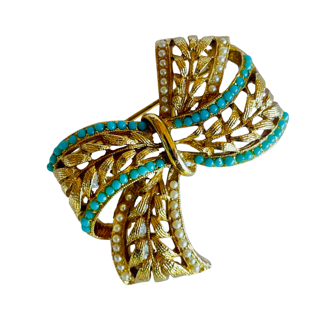 Vintage Sphinx A645 signed bow brooch in gold-tone textured metal with rows of turquoise beads and white faux pearls, showing a 3D ribbon effect.