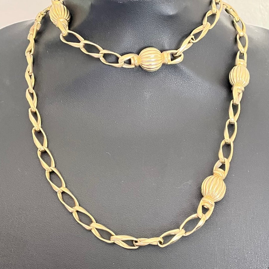 Long gold vintage Christian Dior necklace shown doubled on jewellery bust
