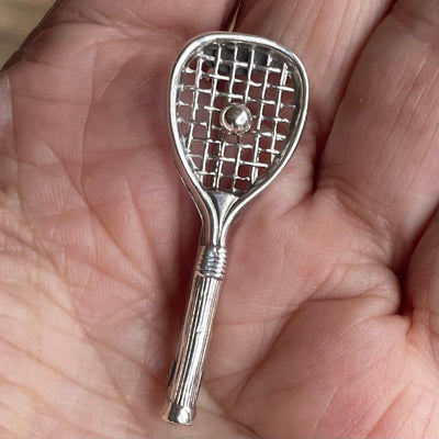 A vintage sterling silver tennis racquet brooch shown held in hand