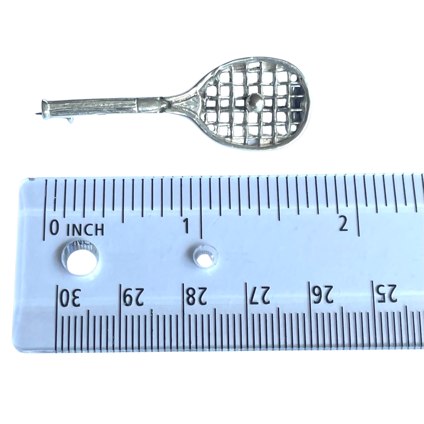 A vintage sterling silver tennis racquet brooch shown with ruler for scale