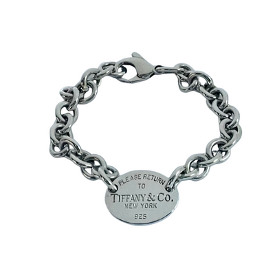 A silver chain bracelet with a round oval tag engraved with 'PLEASE RETURN TO TIFFANY & CO. NEW YORK 925'.