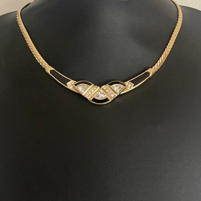 Gold necklace with black accents and gemstones on a black bust.