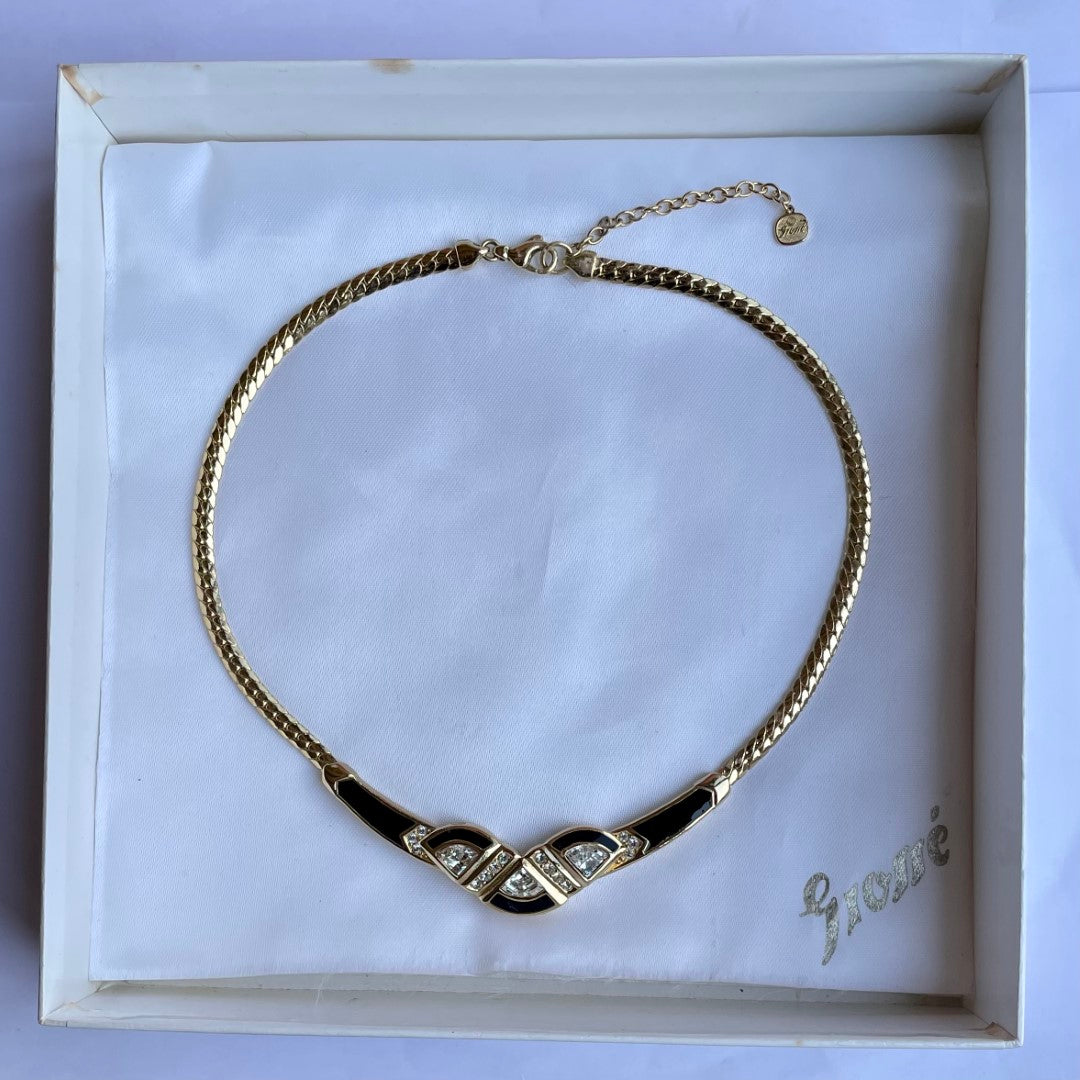 Gold necklace with black accents and gemstones shown in white box with 'Grossé' branding.