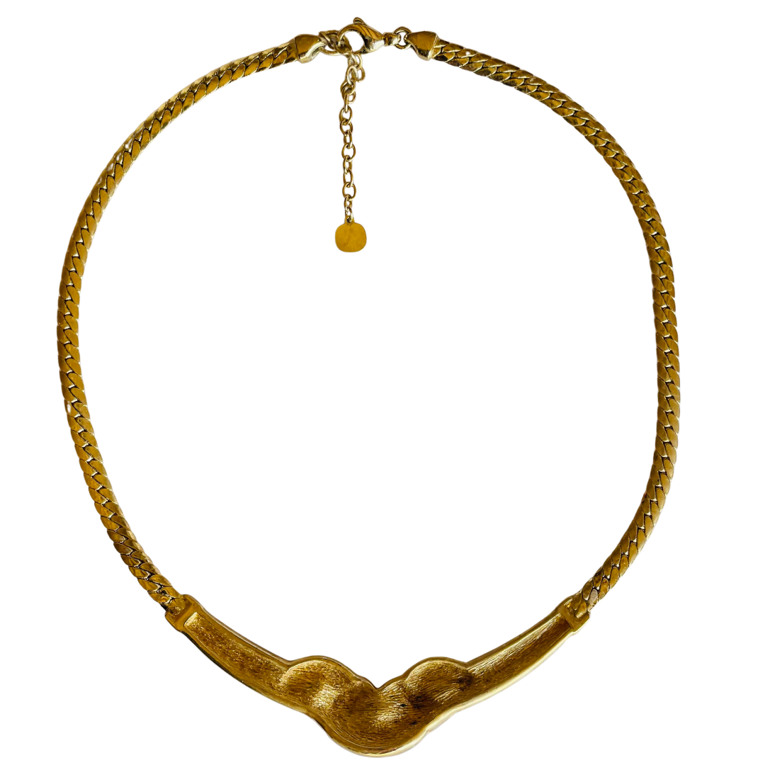 picture shows reverse of gold necklace with black accents and gemstones on a white background