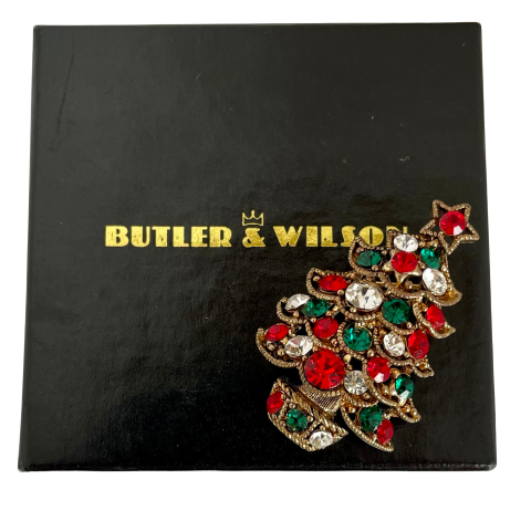 Butler & Wilson Christmas tree brooch with red, green, and gold colors on a black Butler & Wilson box.