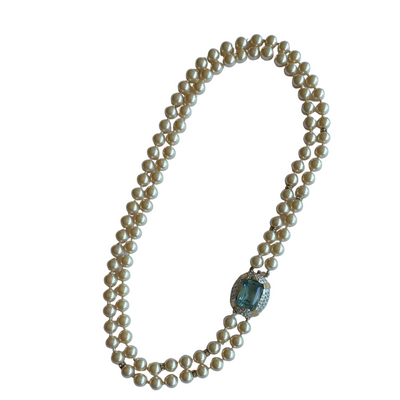 Vintage Vogue Bijoux double-strand faux pearl necklace with 10mm cream pearls, crystal rondelle spacers and an aquamarine crystal pavé-set clasp, 1980s on a white background