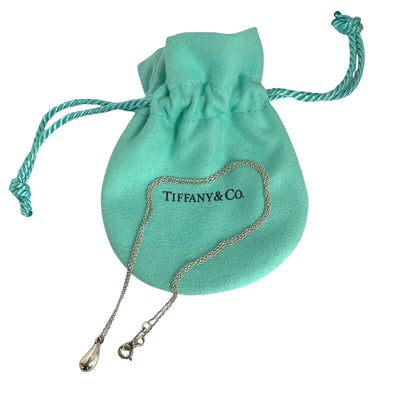 Tiffany and Co. Elsa Peretti sterling silver teardrop pendant necklace shown with blue drawstring pouch on a white background