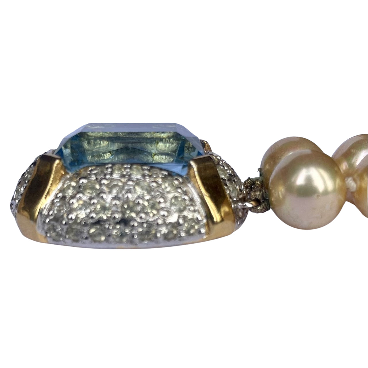 Side profile of a vintage Vogue Bijoux bracelet clasp showing the thick emerald-cut aquamarine crystal, domed rhinestone setting, and attached pearls.