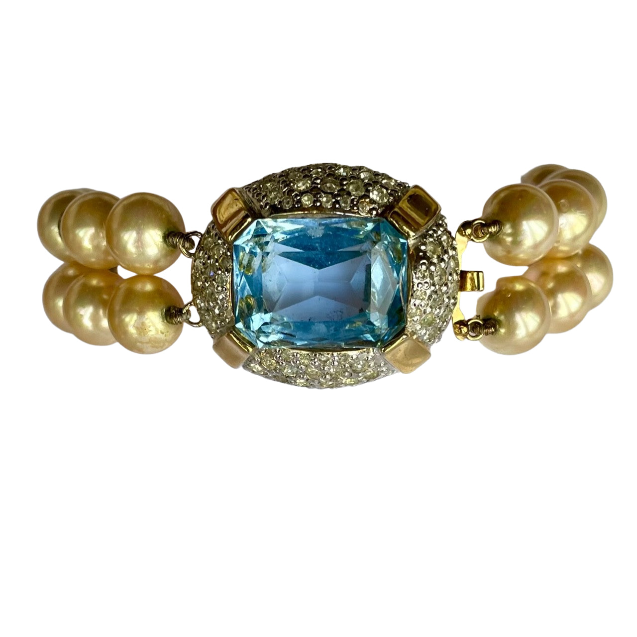 1980s Vogue Bijoux double-strand pearl bracelet. Showcases 10mm cream pearls and a gold clasp with an emerald-cut aquamarine and pavé crystals.