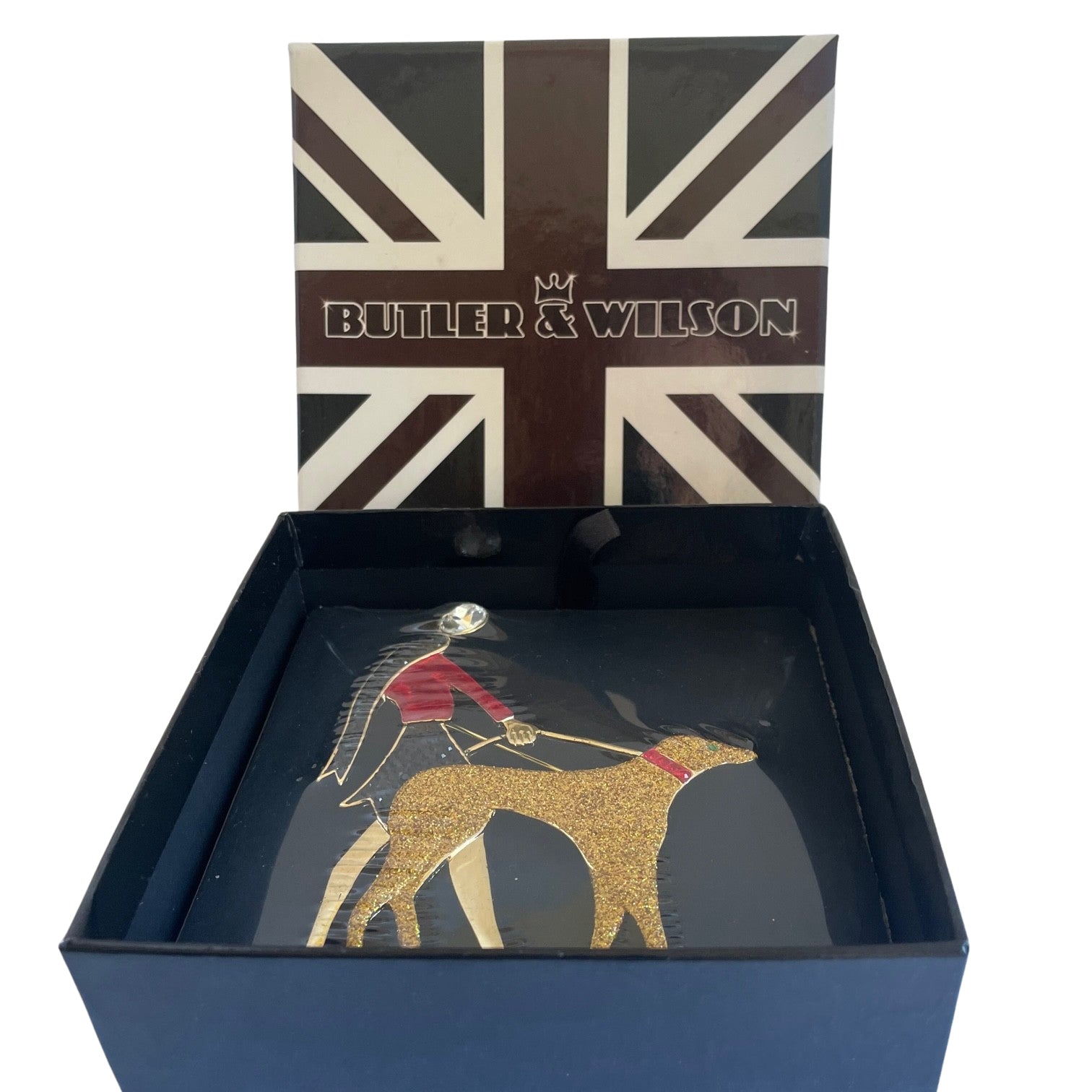 Butler and Wilson Art Deco brooch of a flapper lady in red enamel walking a gold glitter hound dog in a Union Jack box.