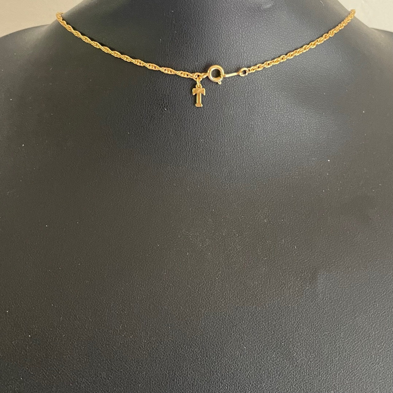 the clasp and Trifari T charm on a vintage mid-century Crown Trifari gold-tone anchor pendant necklace featuring a white enamel finish and an entwined textured marine rope accent.