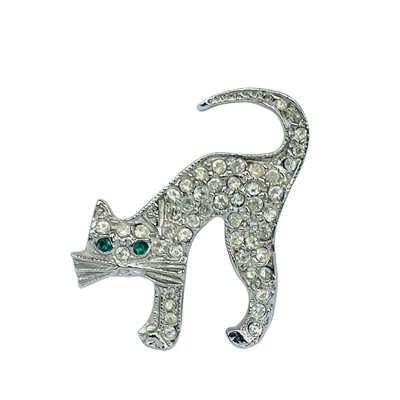A vintage silver-tone Butler and Wilson arched-back cat brooch completely encrusted with clear pavé rhinestones and featuring two striking emerald green crystal eyes.
