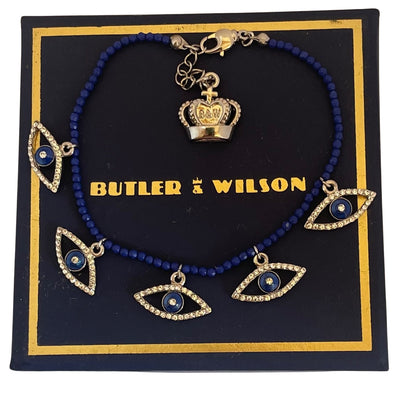 Butler & Wilson crystal eye bracelet with lapis blue beads and crown charm displaying on blue and gold Butler & Wilson box