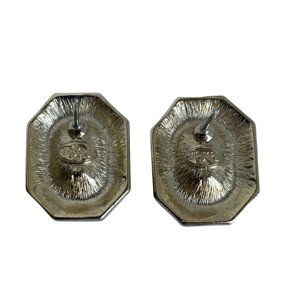 The reverse side of vintage gold-toned Trifari octagonal earrings, showing straight earring posts, a textured finish, and the stamped "TRIFARI©" hallmark.