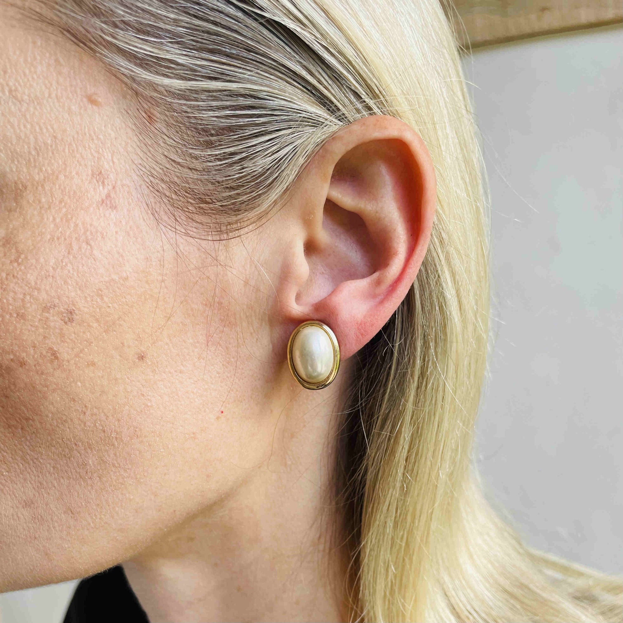 signed Christian Dior Germany vintage jewellery on ear model, showing the size and fit of the classic oval pearl clip earrings.