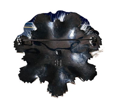 Reverse side of vintage Givenchy snowflake brooch showing the dark japanned finish, a horizontal safety pin clasp, and the stamped 4G logo.
