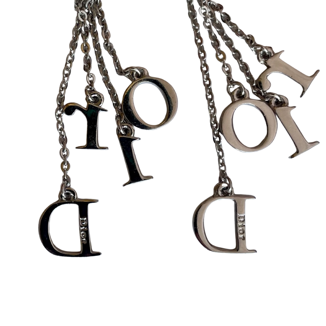 Back view of vintage Dior Galliano era clip-on earrings showing both earrings with screw-back fittings and crystal-set D-I-O-R letter charms on rhodium-plated chains