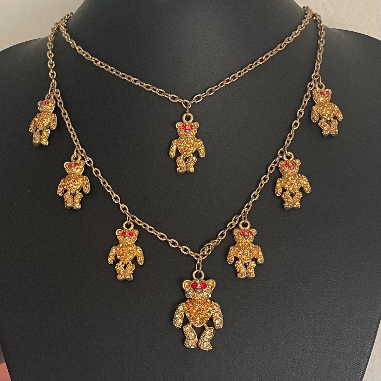 Gold necklace with teddy bear pendants on a black mannequin