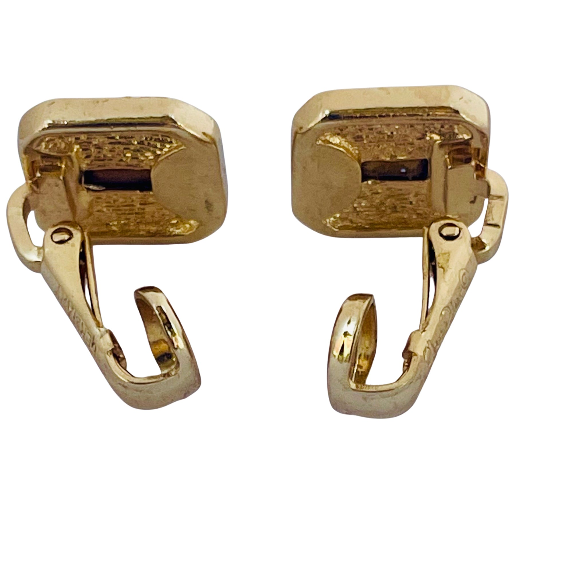 The reverse side of a pair of vintage Christian Dior gold-plated square clip-on earrings shown with the lever mechanism open against a white background, highlighting the texturing on the metal