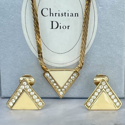Gold-plated Art Deco style Christian Dior geometric triangle necklace and matching clip earrings with clear crystal accents, displayed in front of their light grey Christian Dior box.