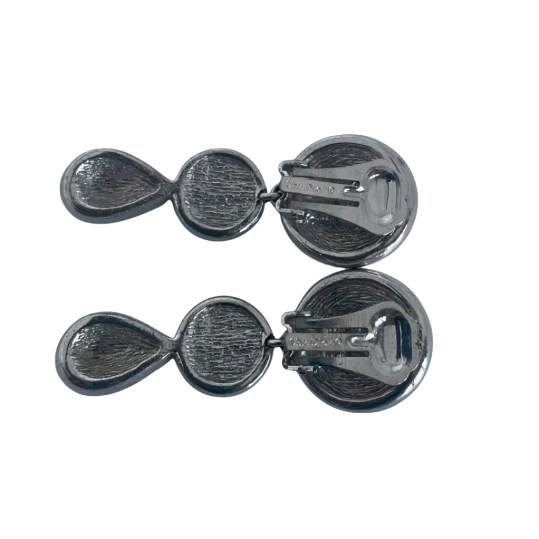 Close-up of a woman wearing vintage 1980s Dior crystal drop earrings with round and teardrop shapes, encrusted with sparkling rhinestones.