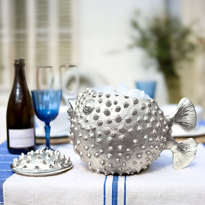 Puffer fish ice bucket shown on a table with wine and glasses in the background