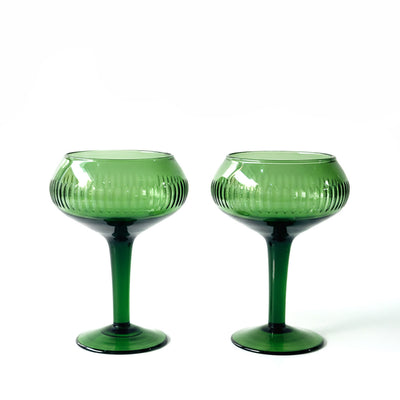 A pair of green glass coupe-style goblets or martini glasses with a ribbed textured bowl and a slender stem, shown on a clean white background.