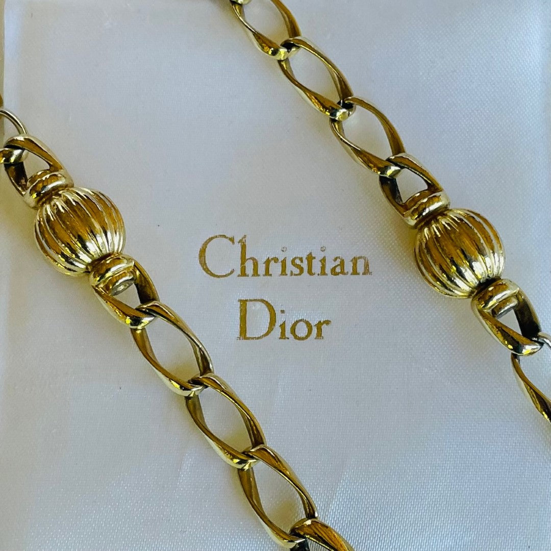 Long gold vintage Christian Dior necklace on a white background with 'Christian Dior' branding.