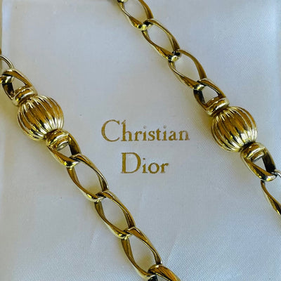 Long gold vintage Christian Dior necklace on a white background with 'Christian Dior' branding.