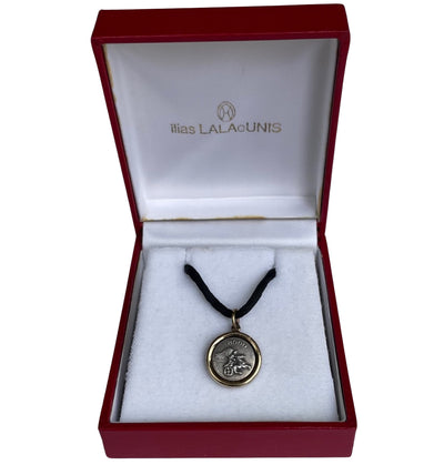 Pristine vintage Ilias Lalaounis necklace showing a 1.6cm 925 sterling silver detailed pendant with an 18K yellow gold border bezel on a 42cm black fabric cord in original Ilias Lalaounis box.