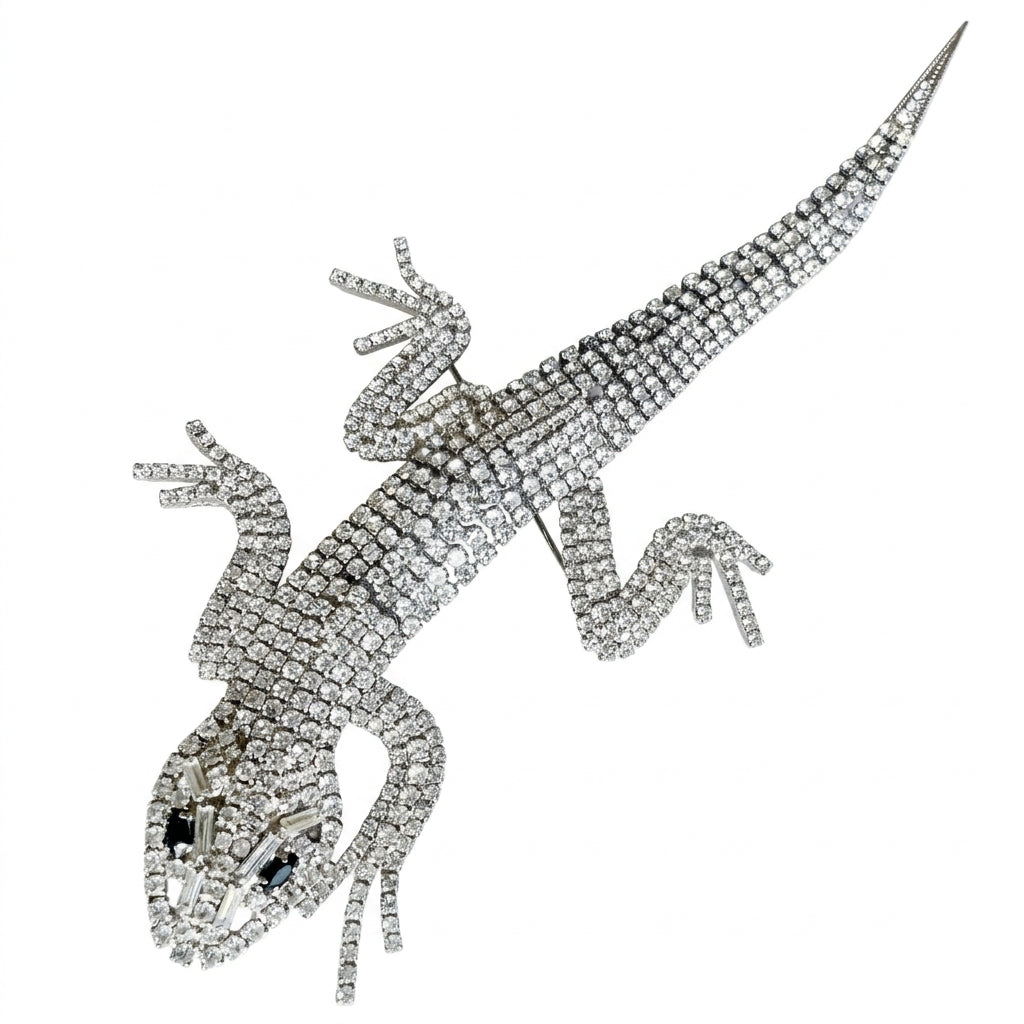 A magnificent 19 cm vintage Butler & Wilson silver-tone articulated lizard brooch encrusted with clear crystals and black eyes, on a white background.