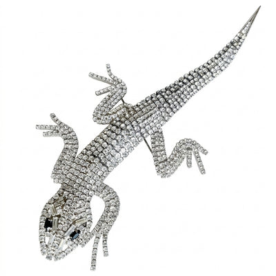 A magnificent 19 cm vintage Butler & Wilson silver-tone articulated lizard brooch encrusted with clear crystals and black eyes, on a white background.