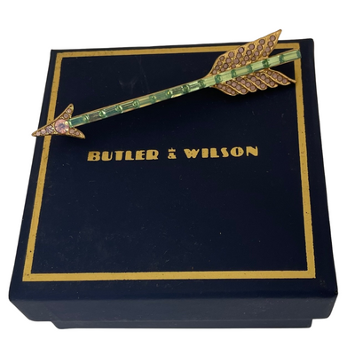 Butler and Wilson crystal arrow brooch displayed next to its original navy and gold presentation box.