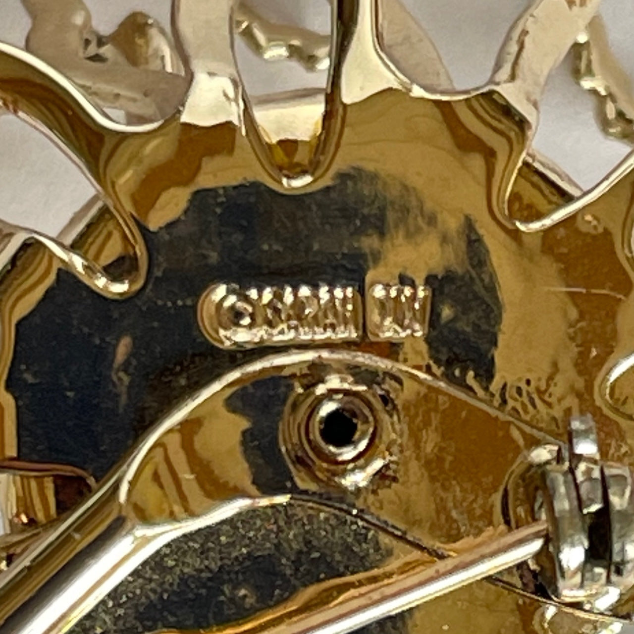 Macro photo of signed ©SARAH COV hallmark stamped on the reverse of a vintage gold brooch
