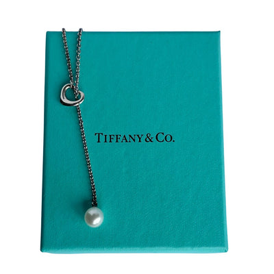 Vintage Tiffany & Co. Elsa Peretti Open Heart sterling silver lariat necklace featuring a sliding open heart pendant and a cultured freshwater pearl on a 19-inch chain, shown in polished pre-owned condition with Tiffany box and pouch.